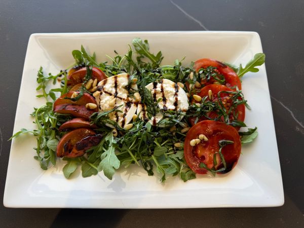 Overhead view of a peach-burrata-arugala salad